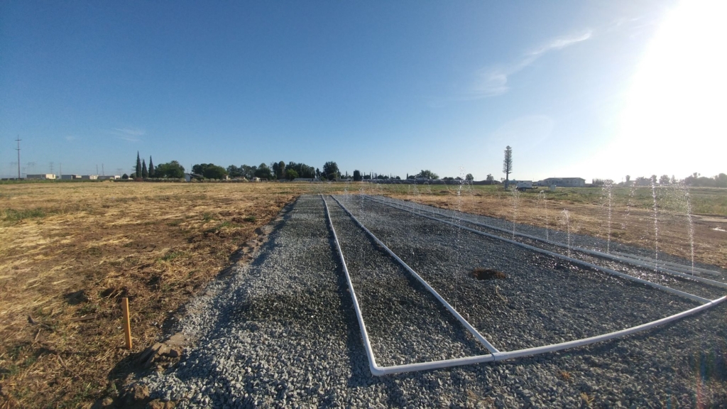 pvc pipes spraying water on gravel field in counry