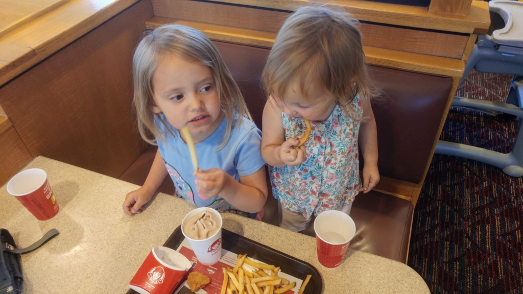 two little girls with fast food in front of them