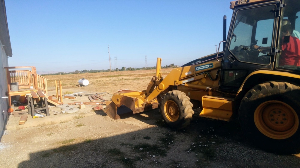 a boy and a man moving dirt in a backhoe