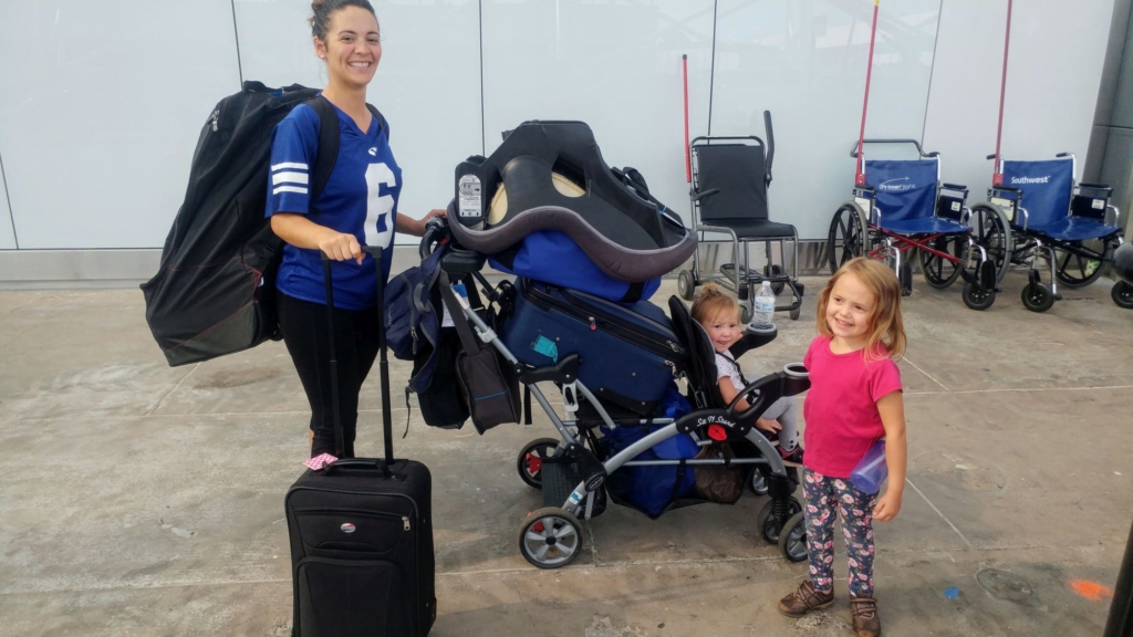 a woman with two little children with a lot of baggage on a stroller