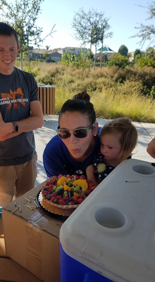 woman blowing out candles with a baby in her arms