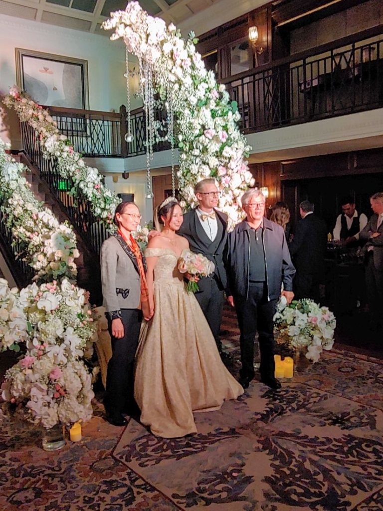 A bride and groom in front of ornate white flowers in the shape of a crecent moon