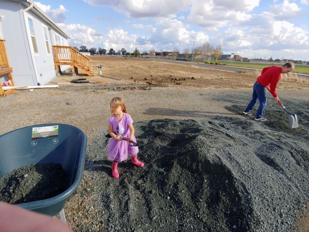 a girl and older man shovelling gravel