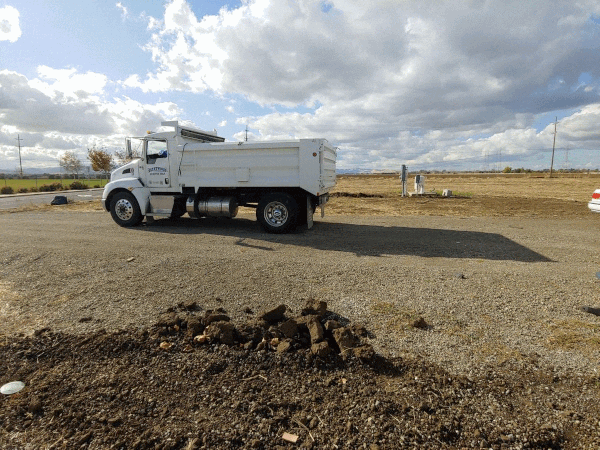 truck dumping gravel on a field